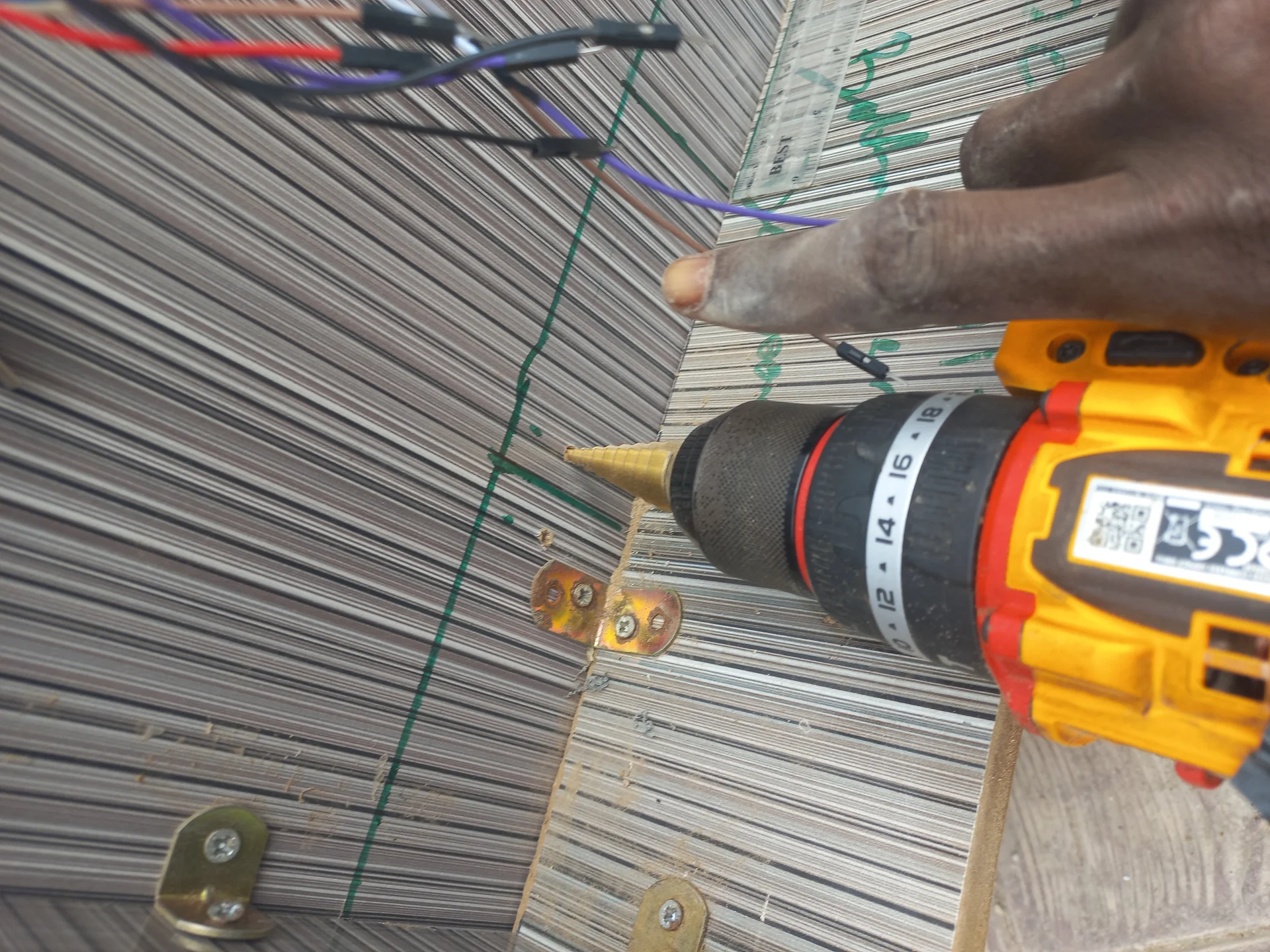Drill driving screws into a hinge along the bin frame edge, with a second hinge already in place further along