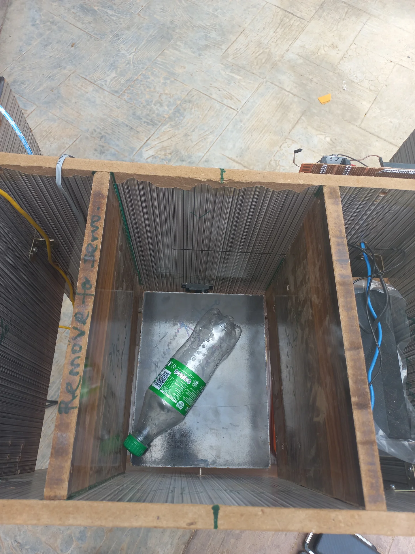 A plastic bottle placed on the sorting tray inside the bin as a test object, confirming the tray size is right