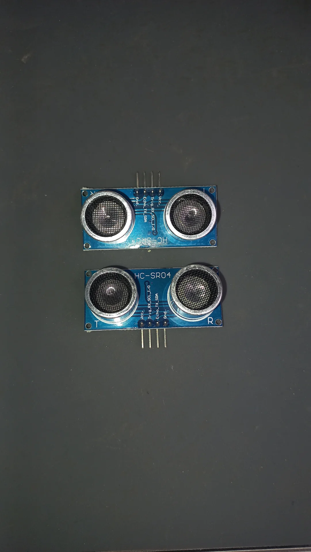 Two HC-SR04 ultrasonic distance sensors stacked one above the other, both showing the twin transducer eyes and HC-SR04 label