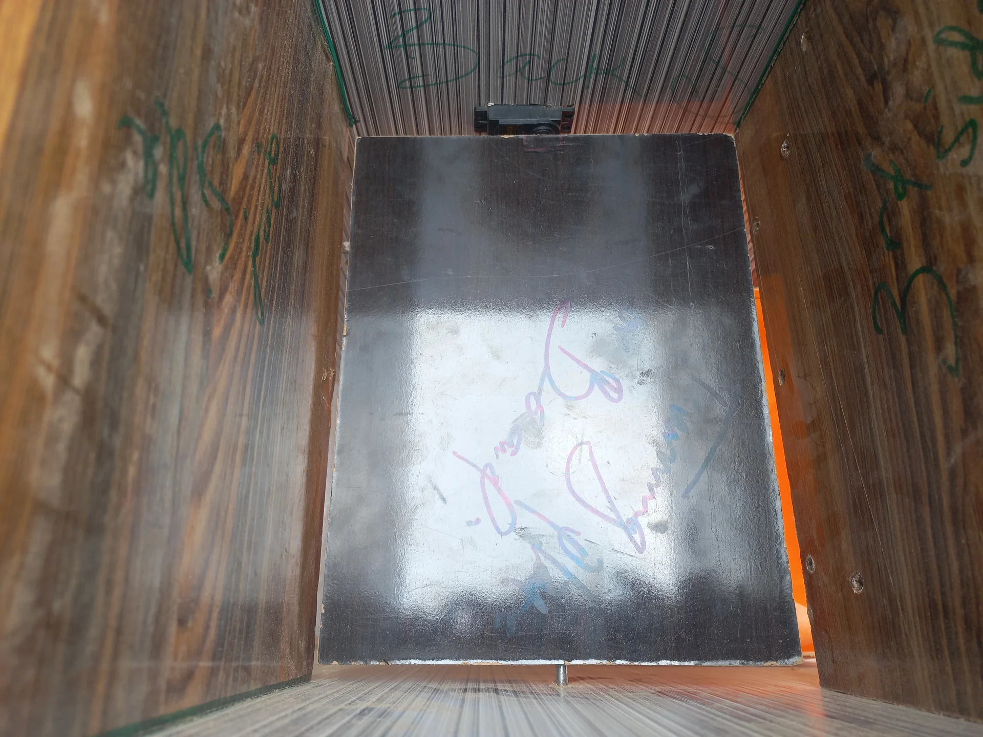 Straight-on view into the compartment showing the silver metallic sorting flap in its closed position, with the servo bracket visible at the top