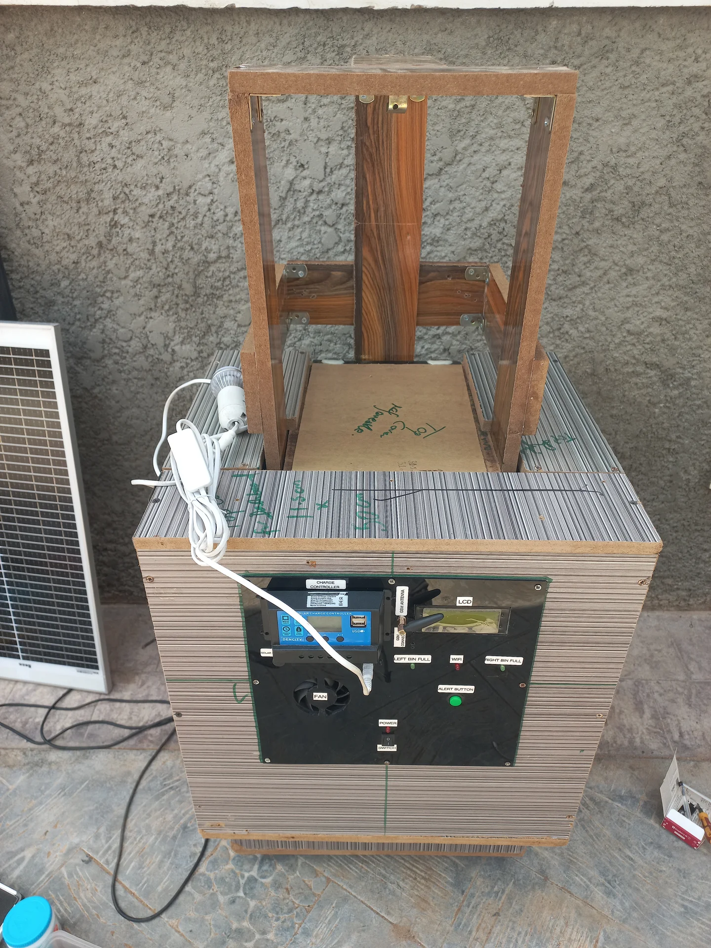 Side view of the bin on its wooden support frame, showing the overhead wooden frame structure above and the electronics panel at the front