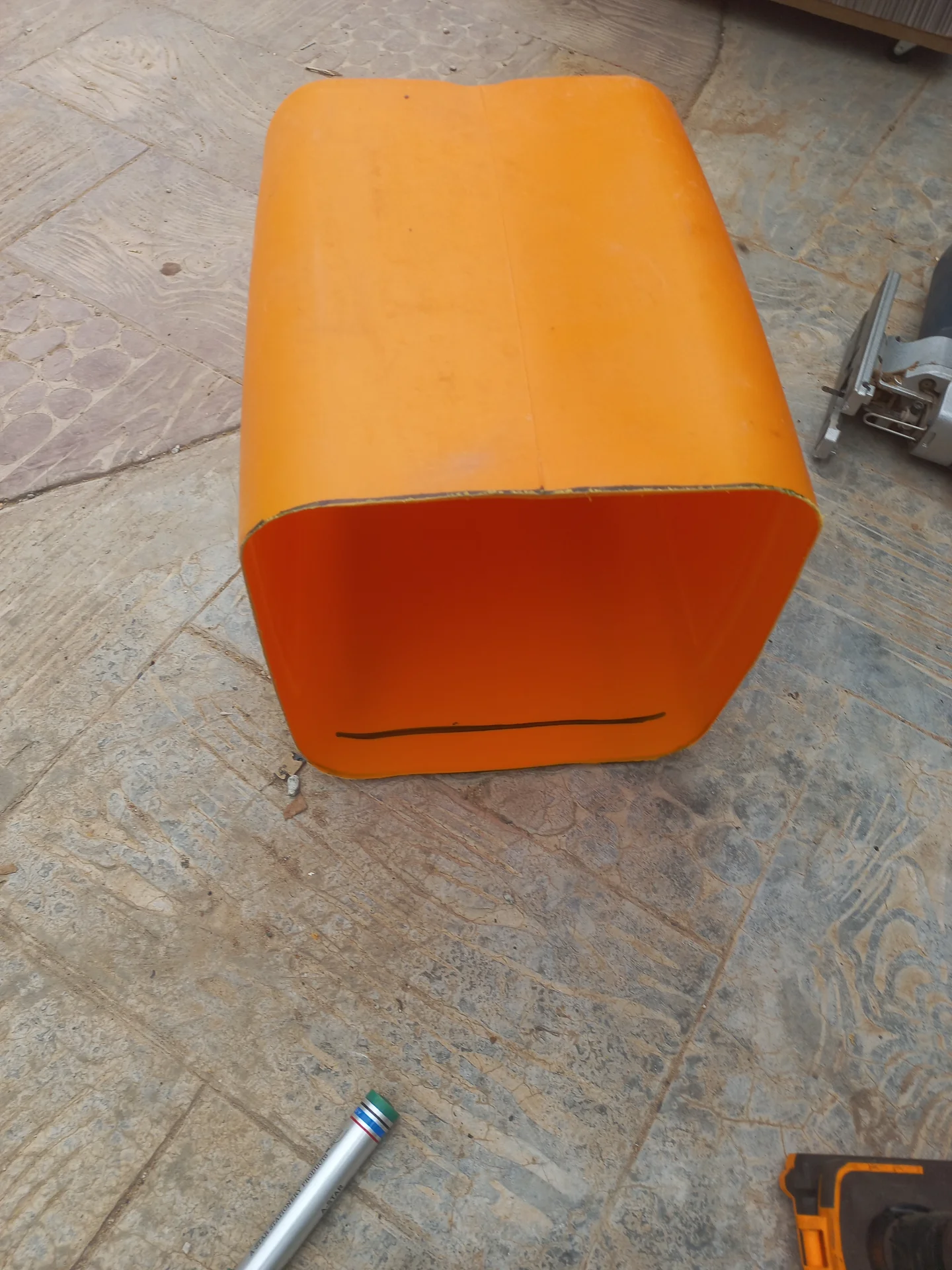The top section of the cut jerry can viewed from the front, with a rectangular slot cut along the lower open edge for cable routing