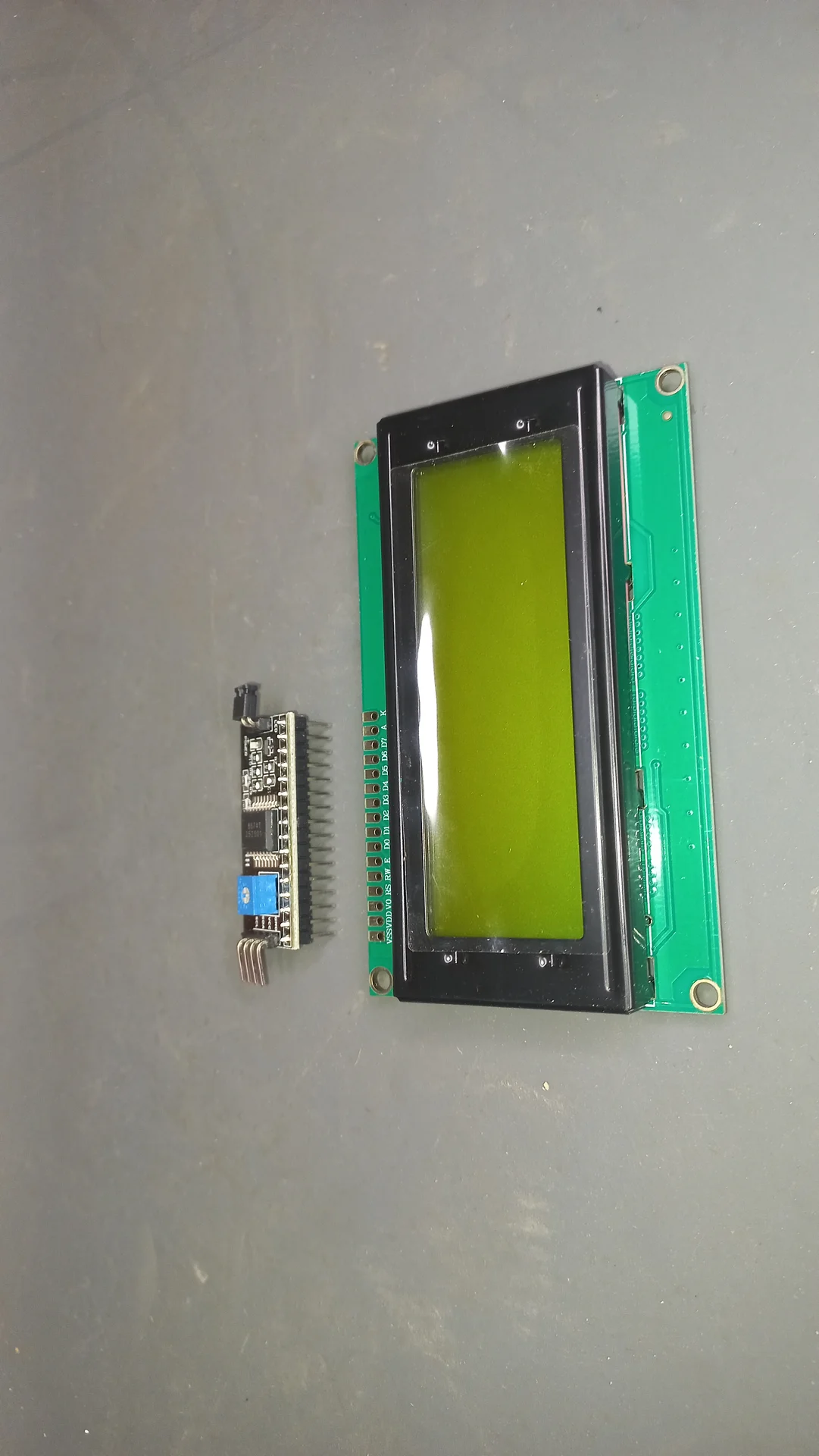 20x4 character LCD display with yellow-green backlight alongside its separate I2C backpack module, before soldering
