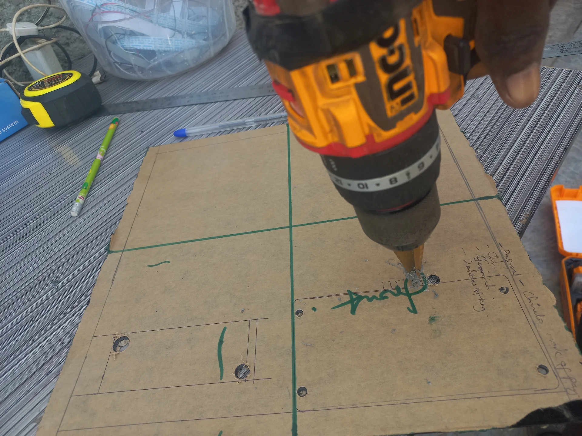 Another angle of the panel drilling process, showing the drill bit going through the panel board