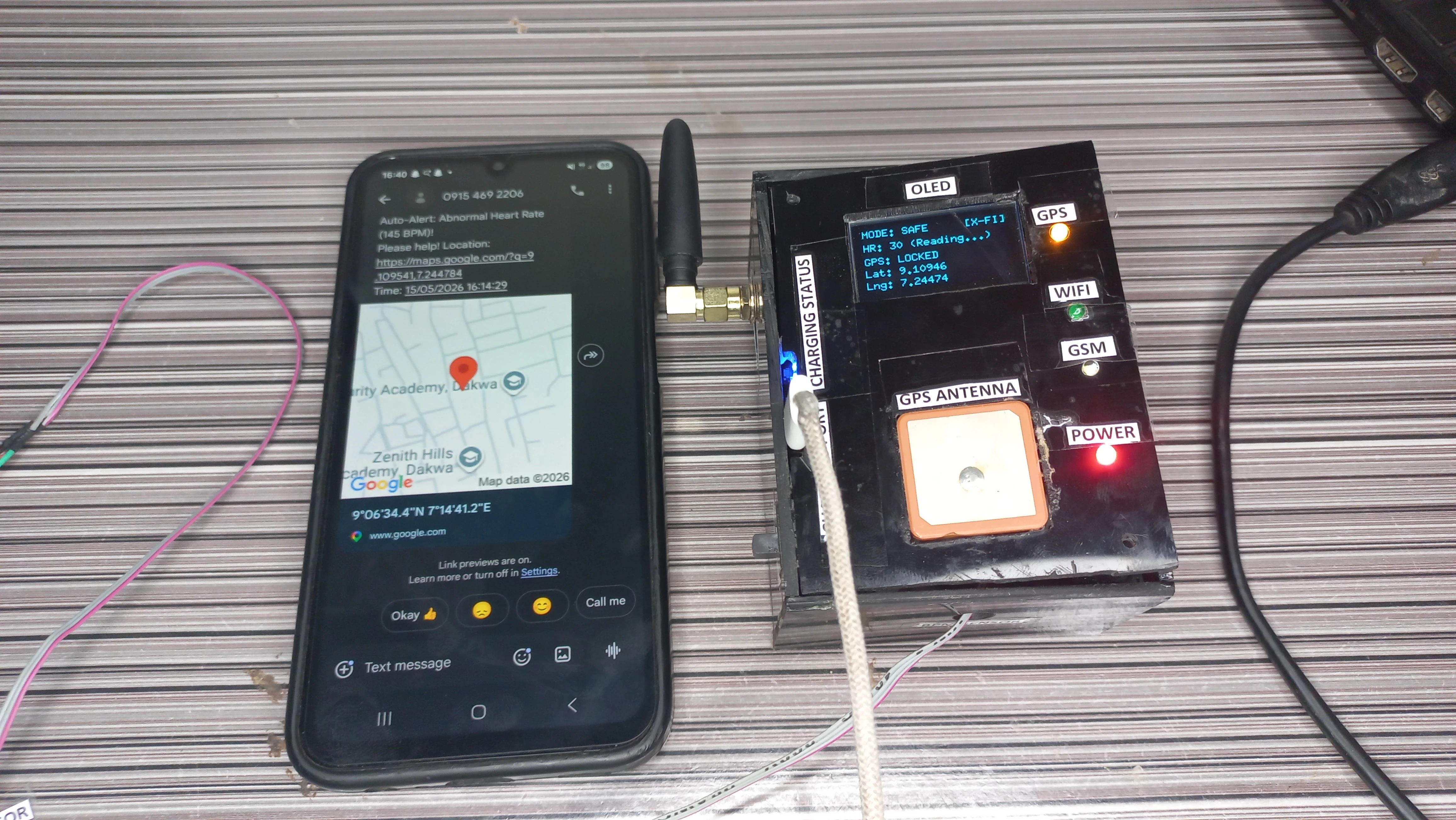 Live demonstration: device OLED showing GPS lock and heart rate, smartphone displaying received SMS with Google Maps location pin