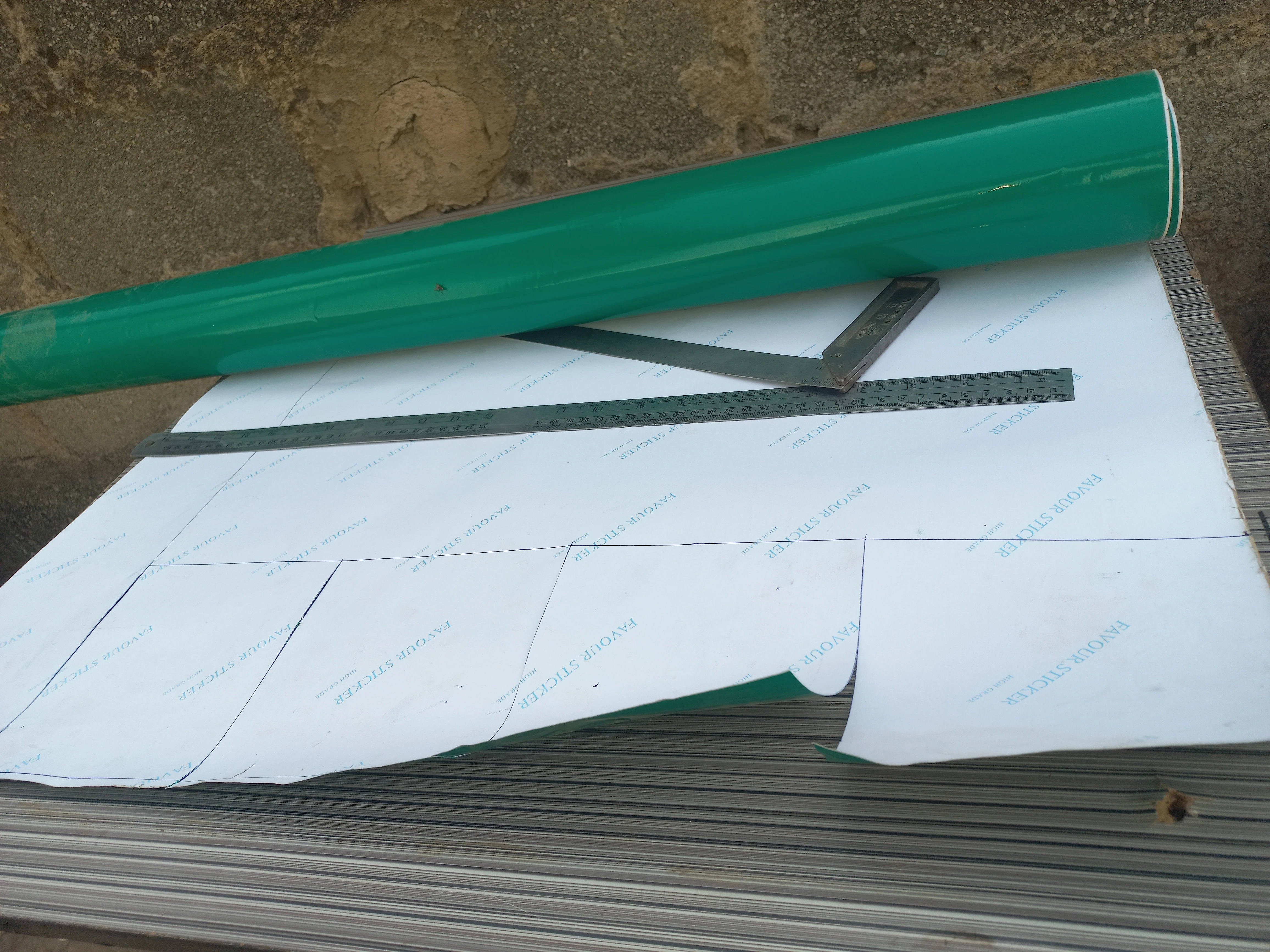 Green vinyl roll and cut foam pieces prepared for the four corner grass areas of the model