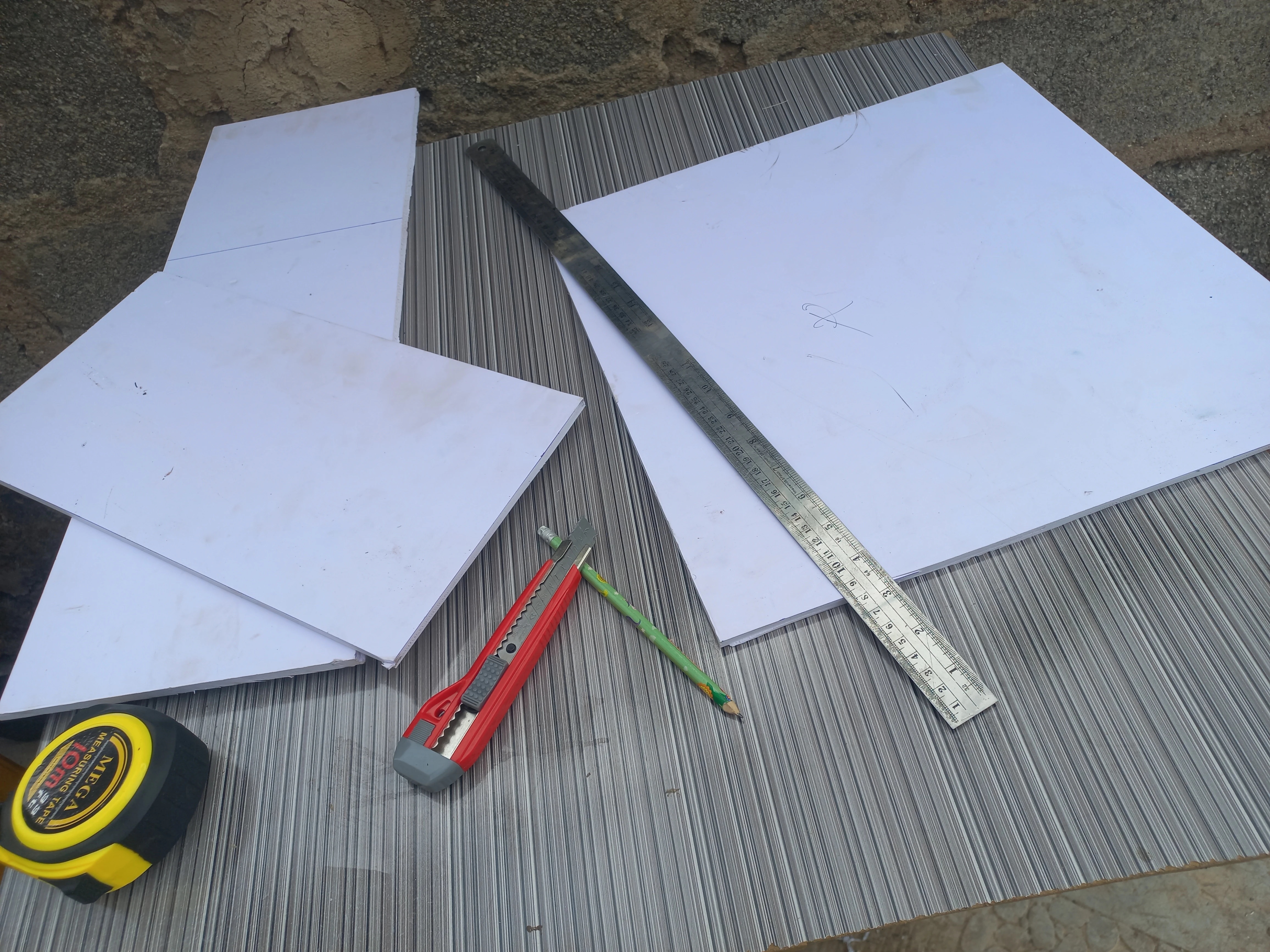 PVC board on workbench with hacksaw, set square, and marker: material preparation for the road model base board