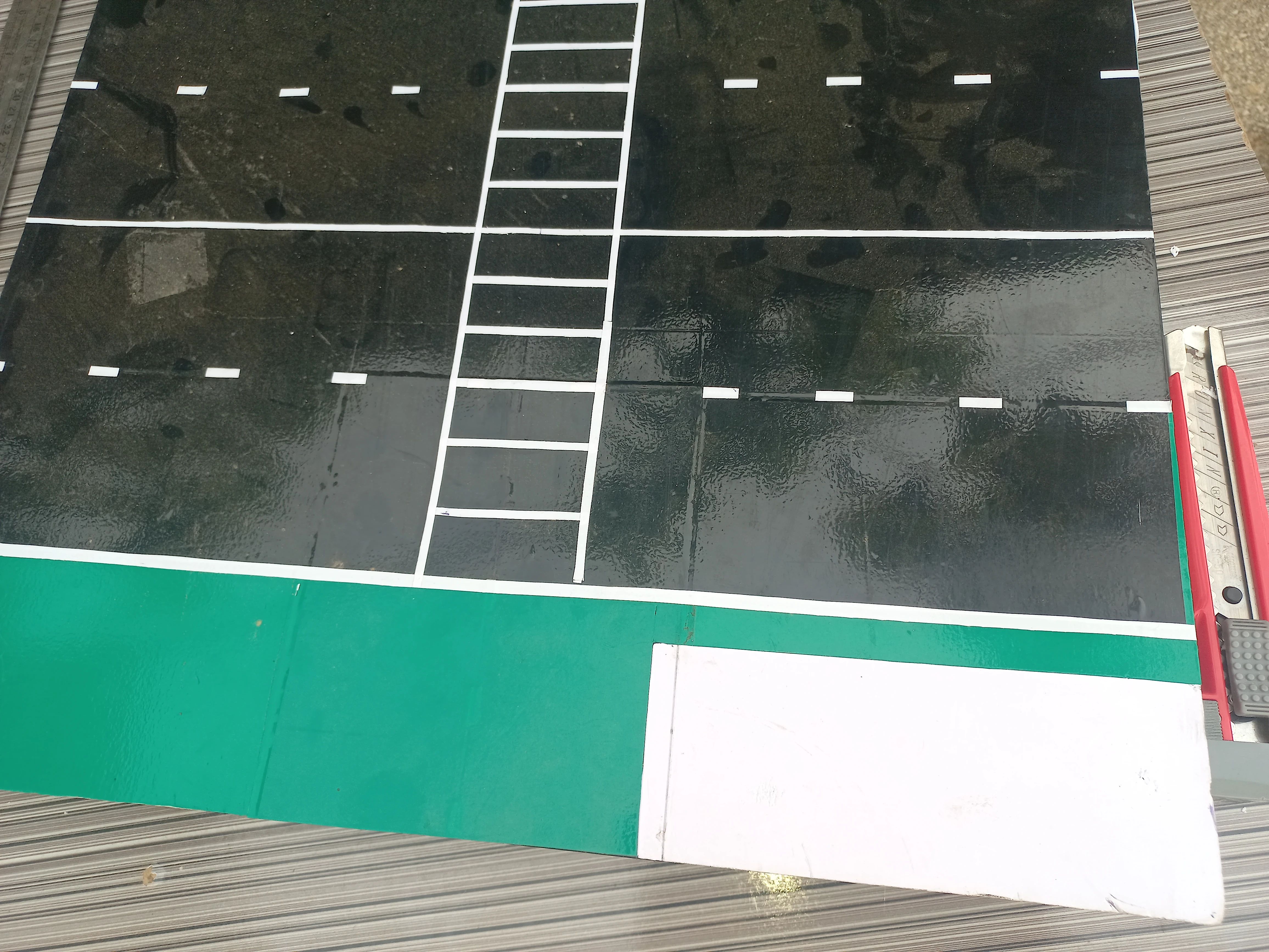Road model under construction with traffic light post assemblies being fitted at the crossroads corners